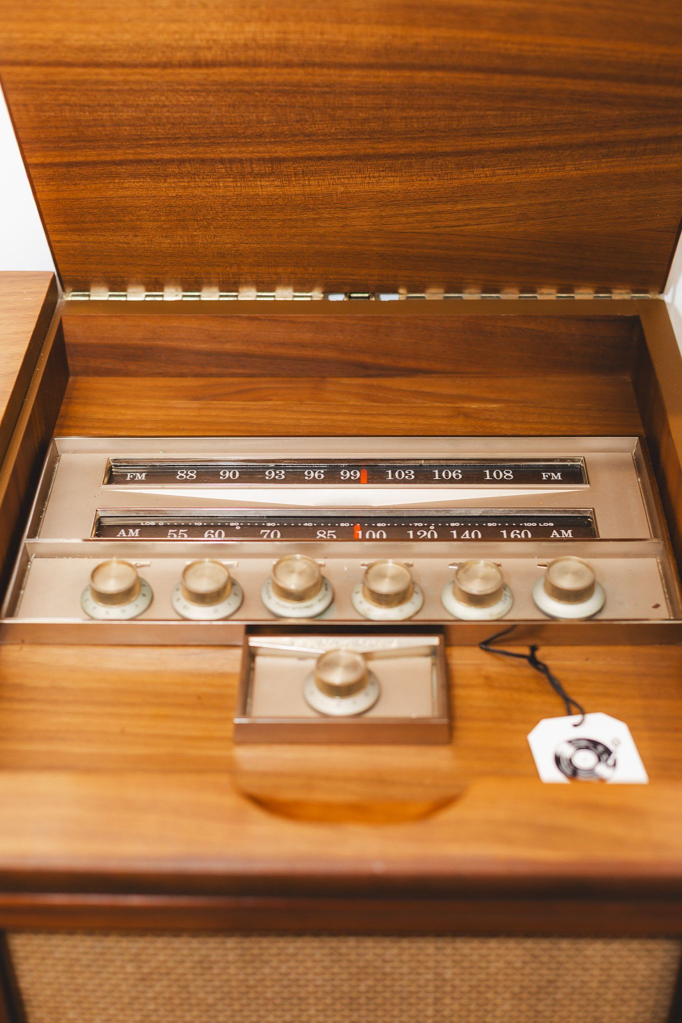 Console lid lifted to show the AM and FM radio dial and brass knobs
